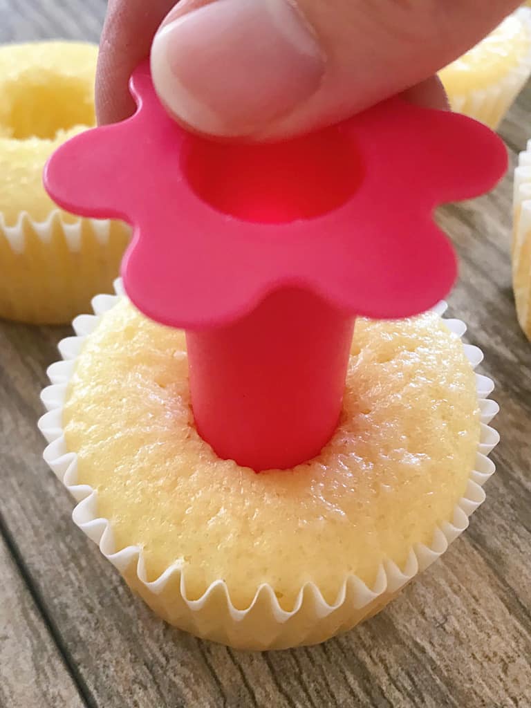 A cupcake corer removing the center of a pineapple cupcake.