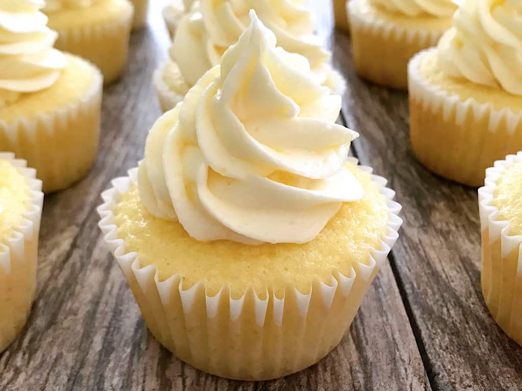 Pineapple Cupcakes with pineapple frosting on a wood backdrop.