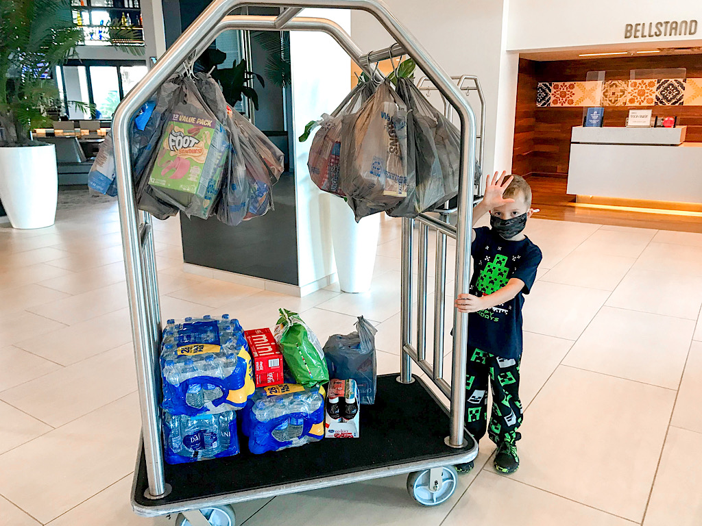 A boy with a luggage cart full of groceries at a Disney resort hotel.