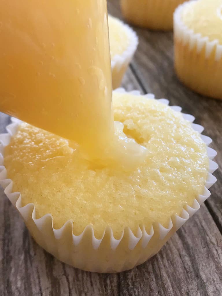 Pineapple filling being piped into pineapple Dole Whip Cupcakes.