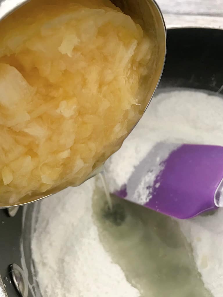 Crushed pineapple being added to a pan.