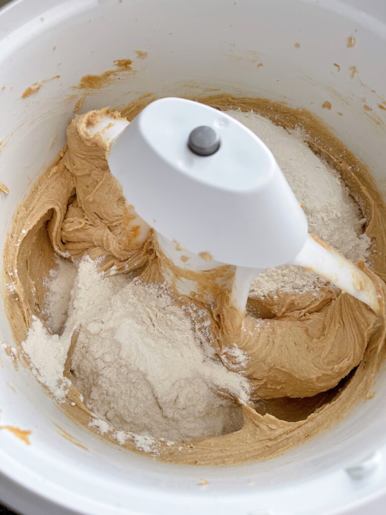 Wet and dry ingredients for peanut butter cookie dough in a stand mixer.