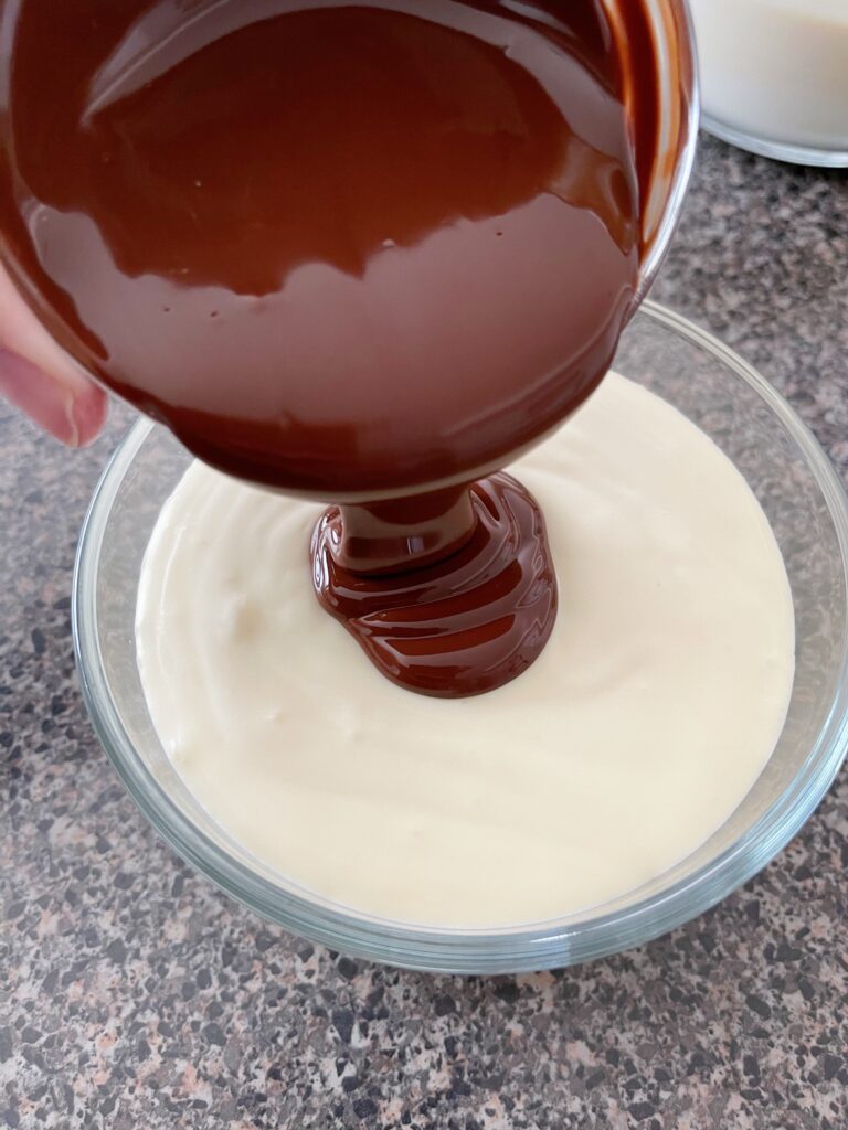 Melted chocolate poured into a bowl of cheesecake batter.