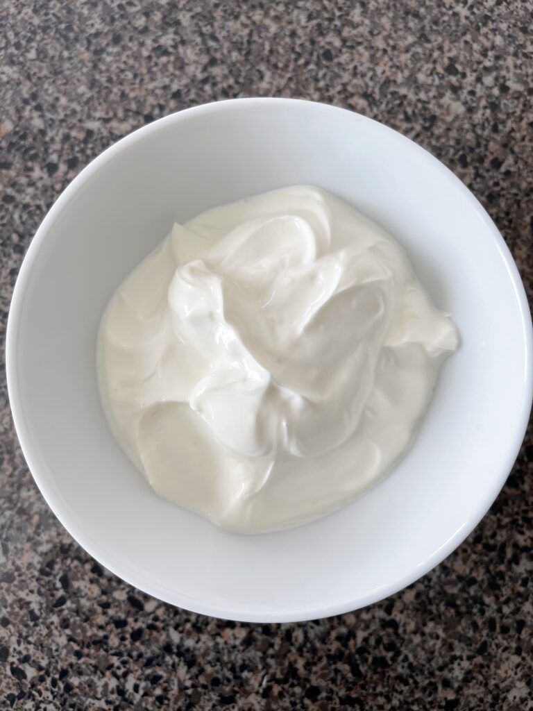 A white bowl of sour cream.