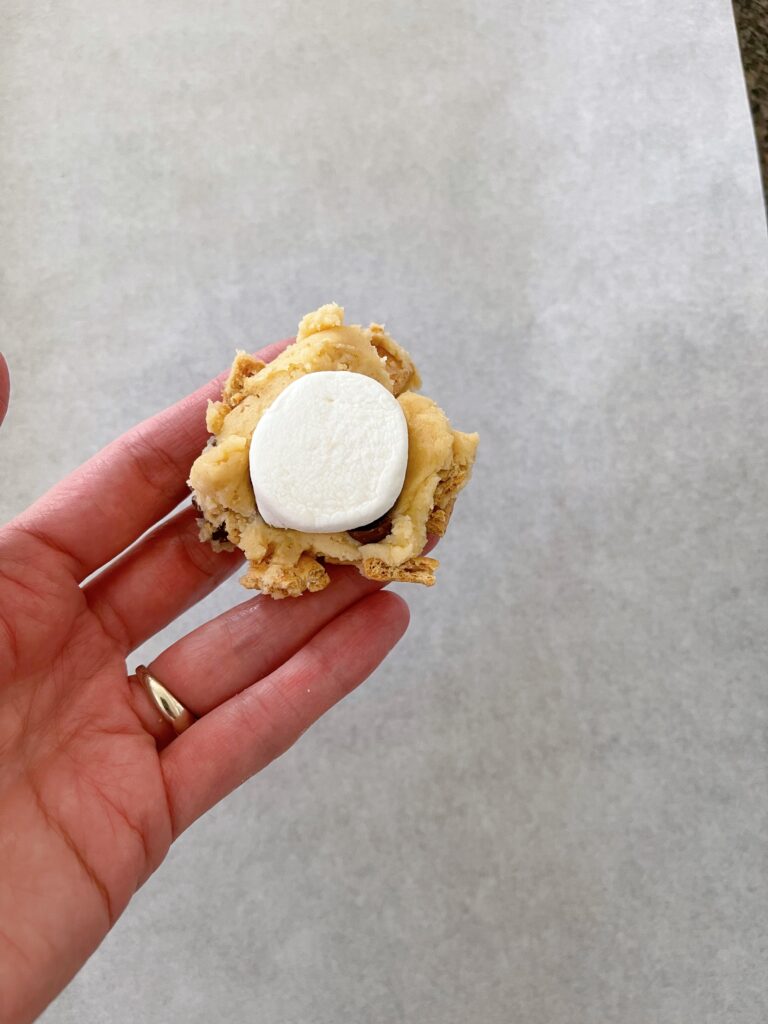 Cookie dough being wrapped around a jumbo marshmallow.