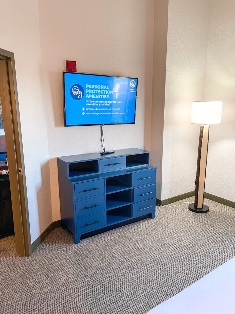 Dresser, television, and floor lamp inside the master bedroom of a Grizzly Bear Suite.