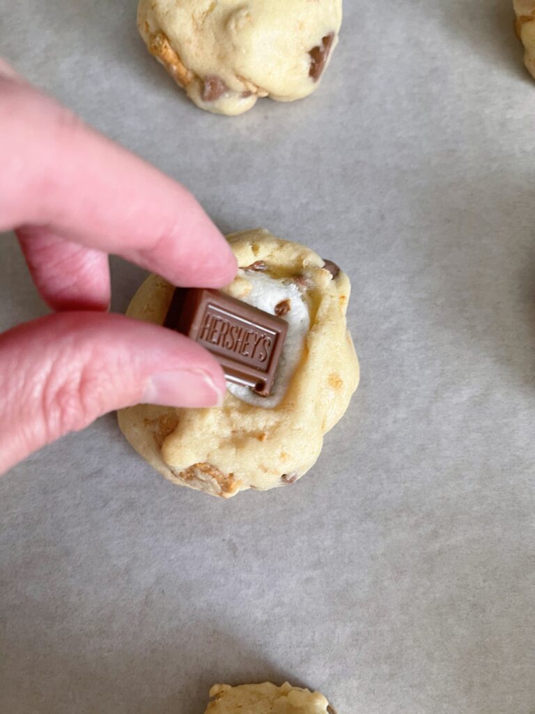 Putting a Hershey chocolate bar on S'mores cookies.