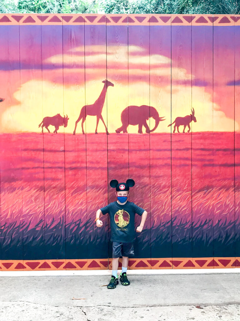 Un niño con orejas de Mickey frente a un letrero de Rey León en Disney's Animal Kingdom.