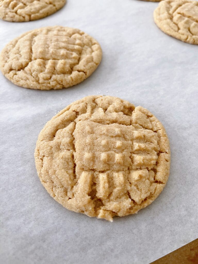 Freshly baked peanut butter cookies on parchment paper.