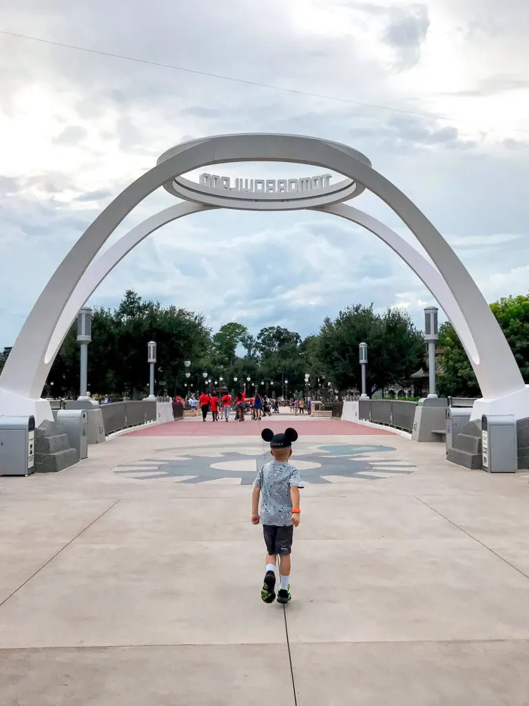 A boy in a Mickey hat in front of Tomorrowland.