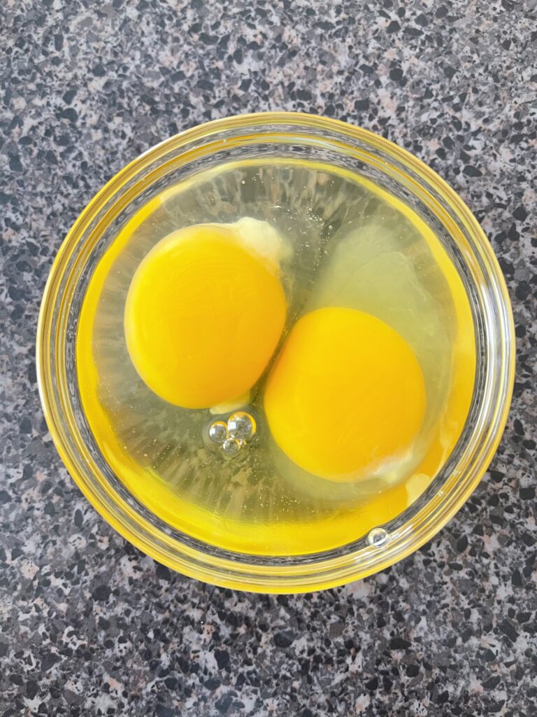 A bowl with two eggs in it.