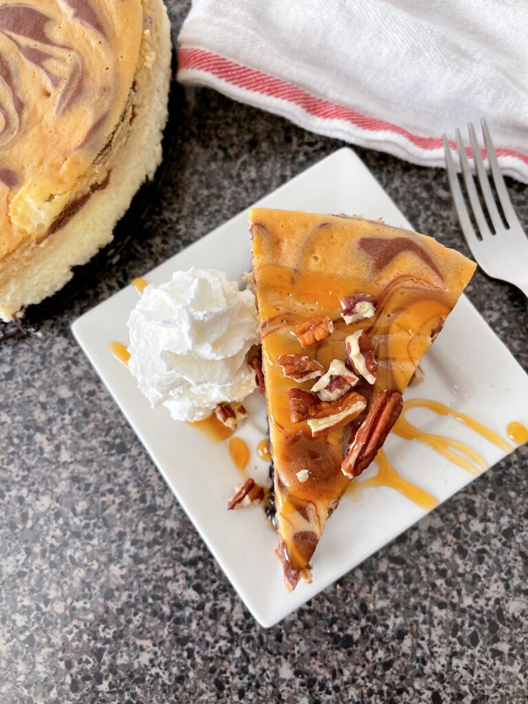 A slice of Cheesecake Factory Caramel Pecan Turtle Cheesecake with whipped cream and caramel sauce.