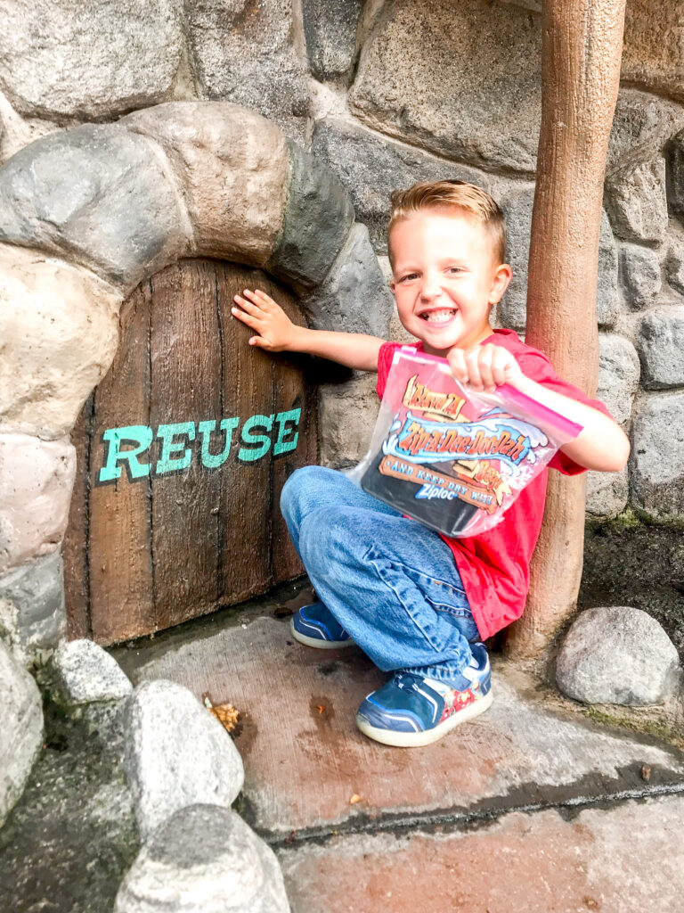 A boy outside Splash Mountain holding a Ziploc Bag.