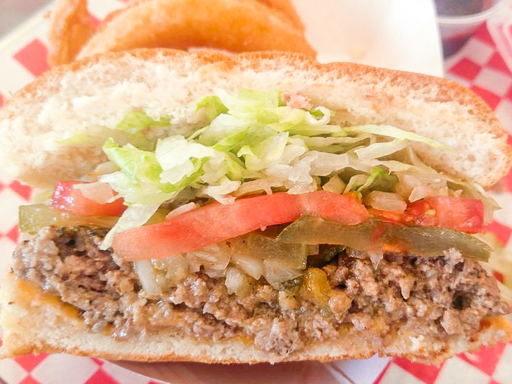 A hamburger with lettuce, tomatoes, and pickles, from Biggie's Burgers in San Diego.