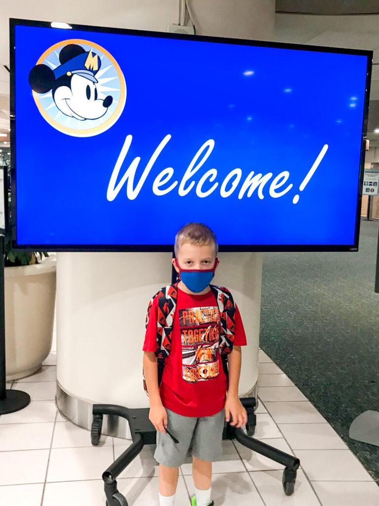 Un niño frente a un cartel de bienvenida de Disney.