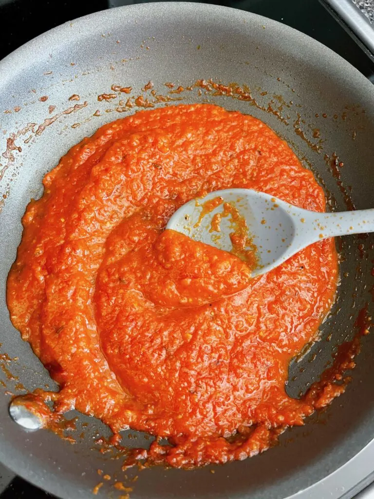 Gyro red sauce in a pan with a spoon.