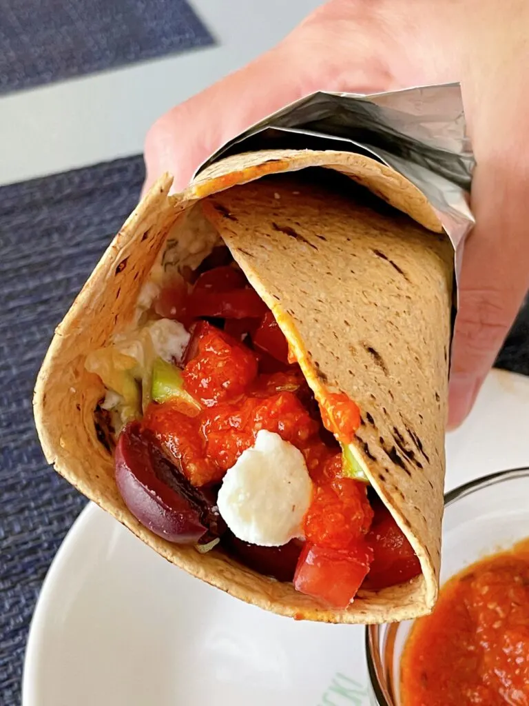 A veggie gyro with tzatziki and red sauce.