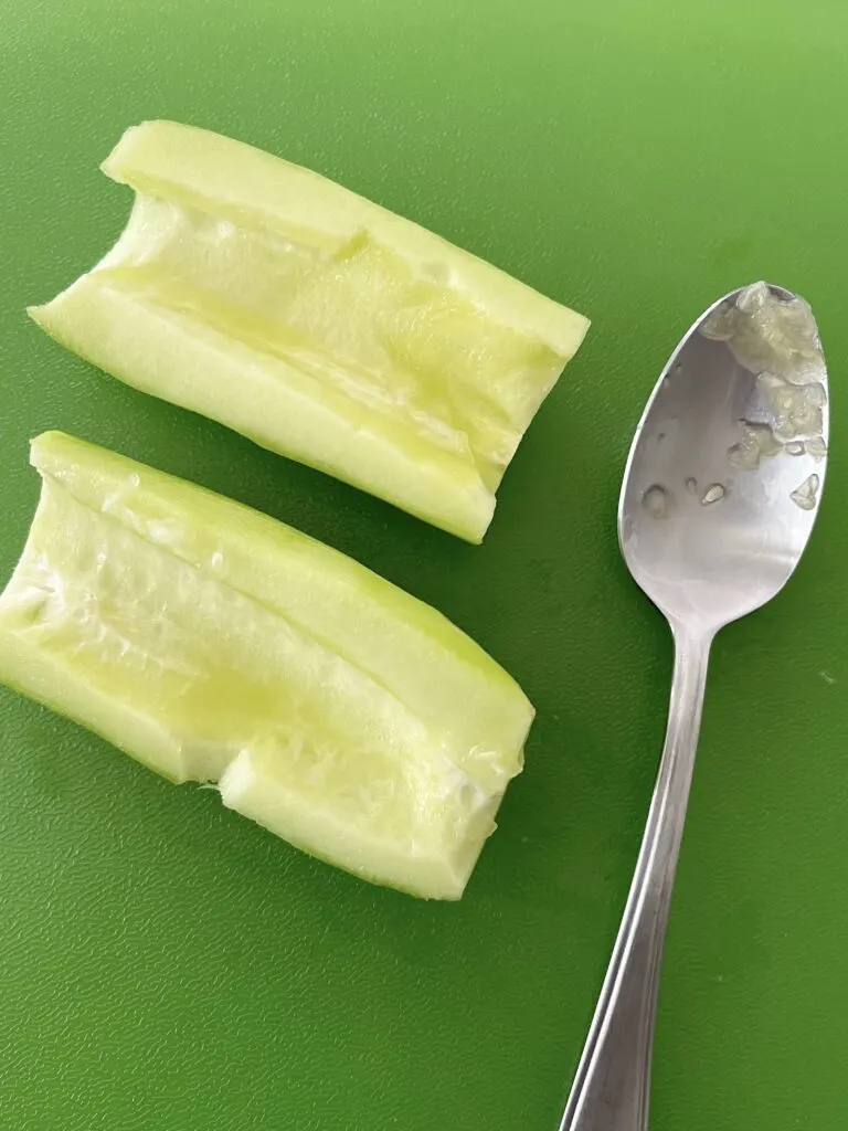 Two cucumber halves with seeds removed by a spoon.