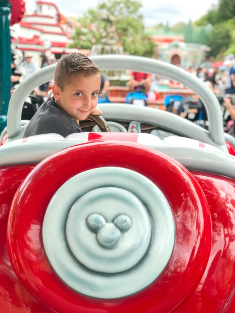 A boy in a Mickey Mouse car in Toon Town at Disneyland.