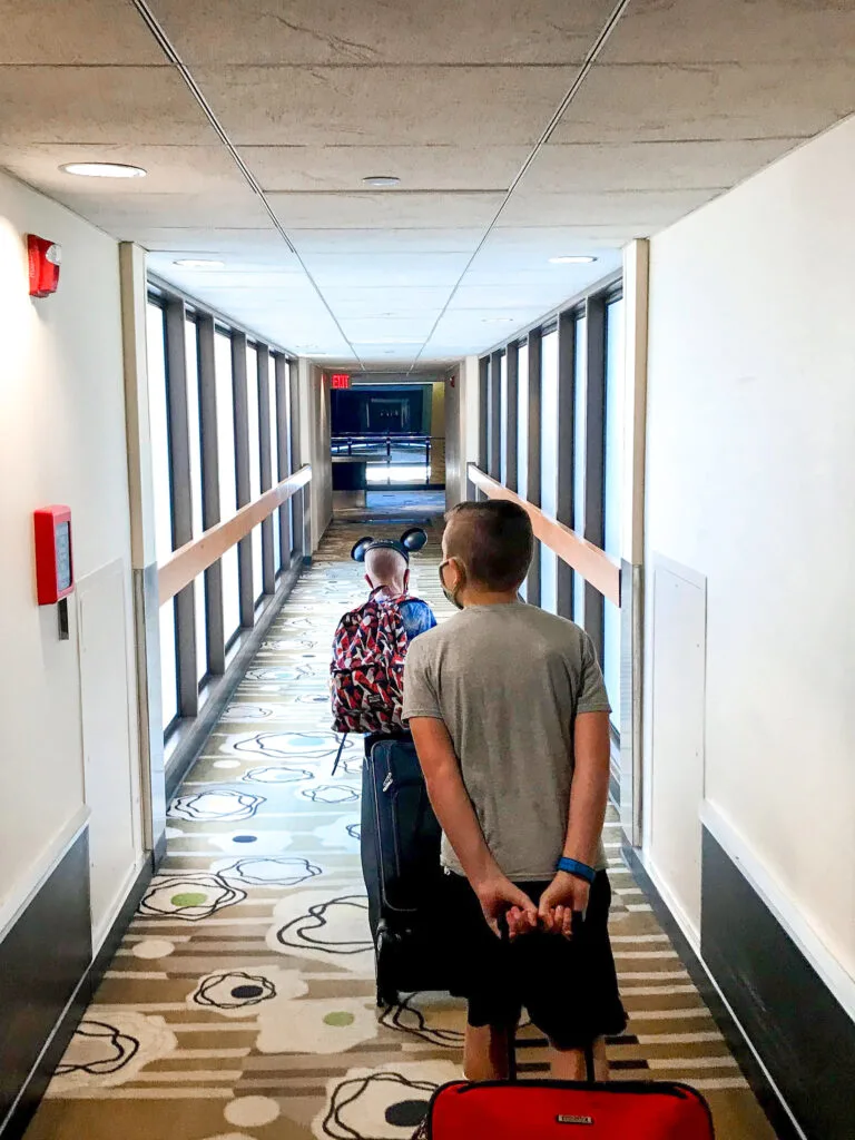 Two kids pulling suitcases down the hallway at Disney's Contemporary Resort.