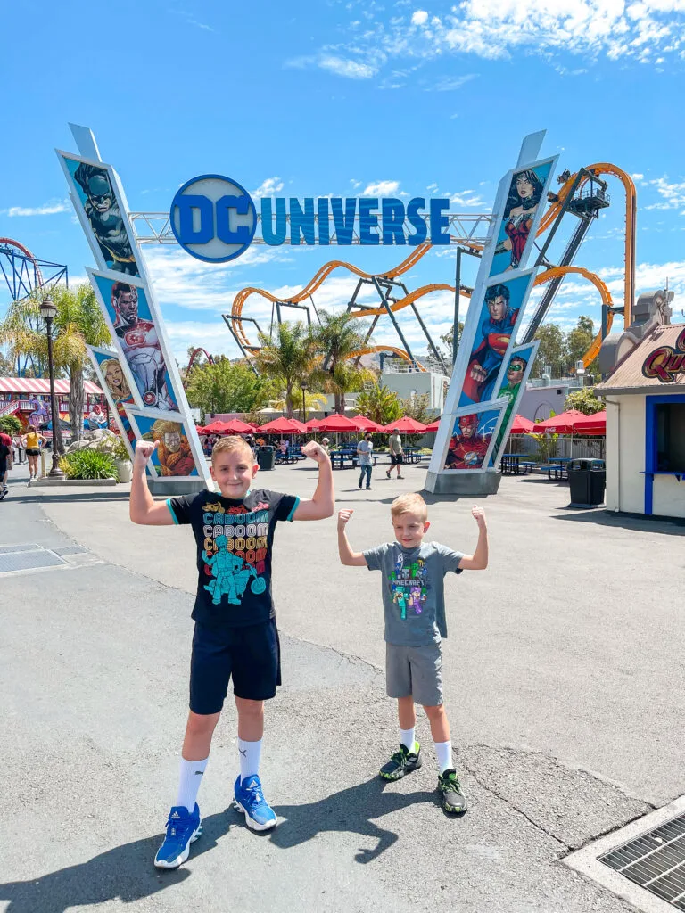 Two kids in front of a DC Universe sign at Six Flags Discovery Kingdom.