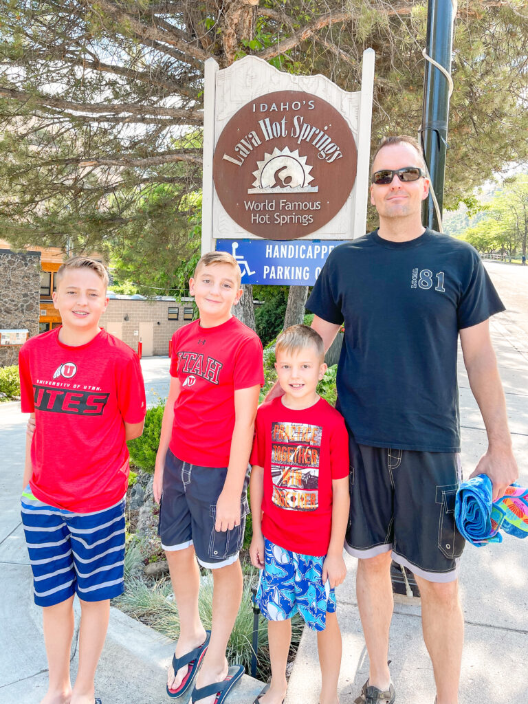 A family standing by a sign for Lava Hot Springs.