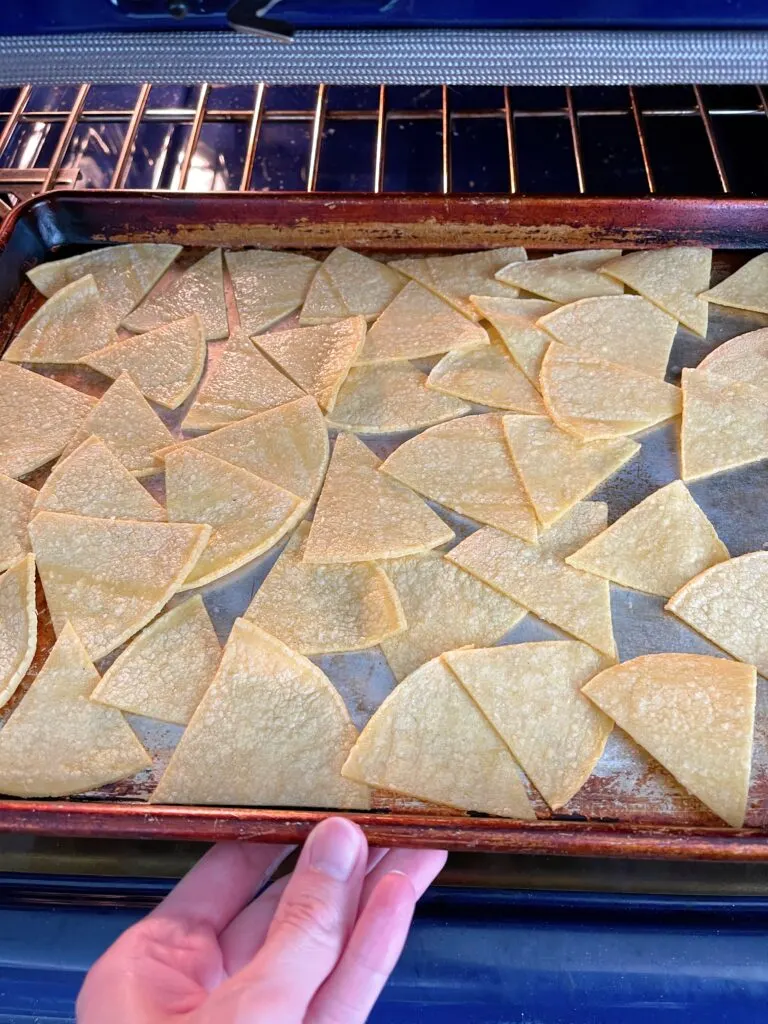 Placing a pan of tortilla chips in the oven.