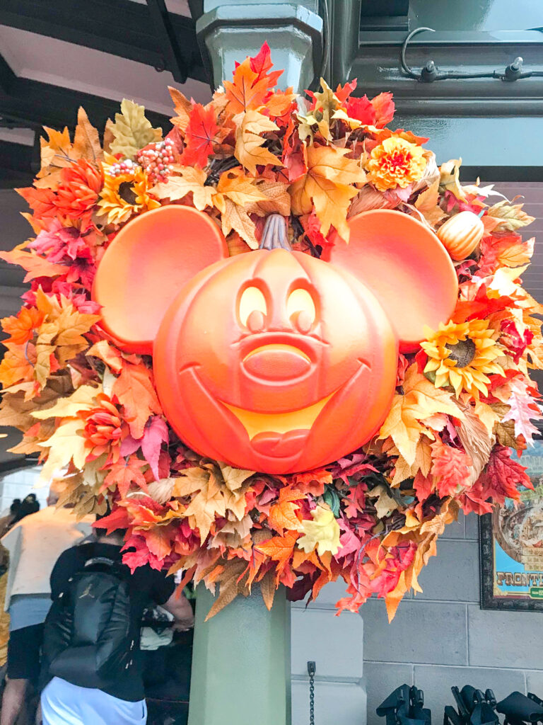 A Mickey Mouse shaped pumpkin in the center of a wreath.