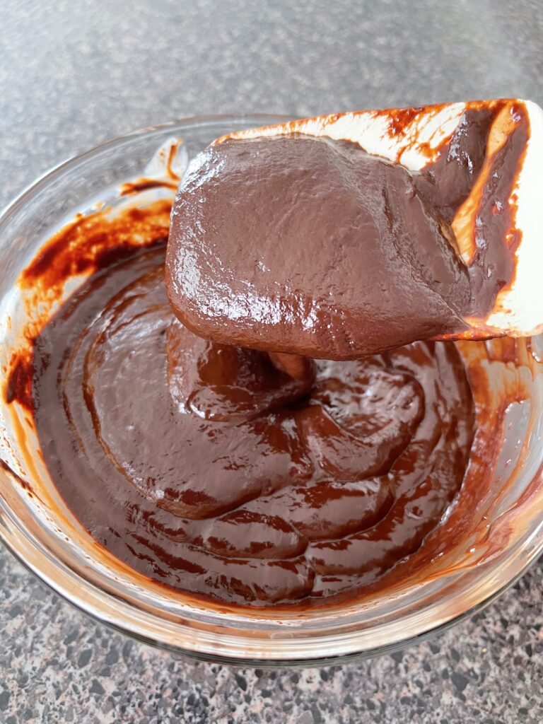 A bowl of chocolate ganache and a spatula.