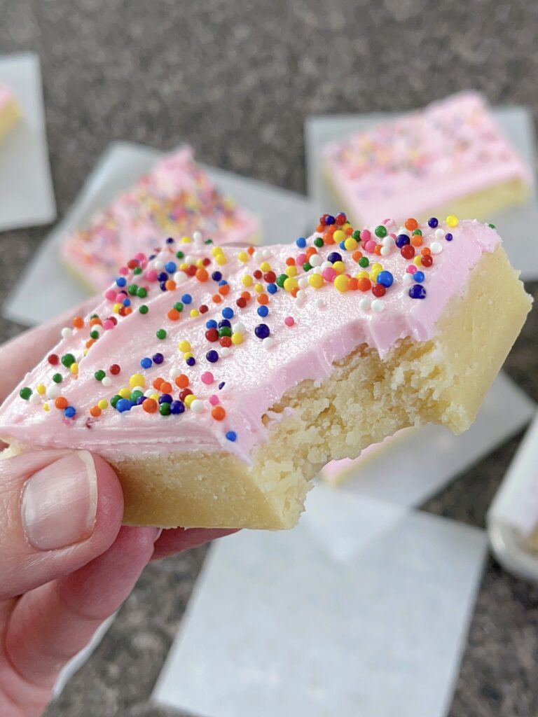 A cream cheese sugar cookie bar with a bite taken out.