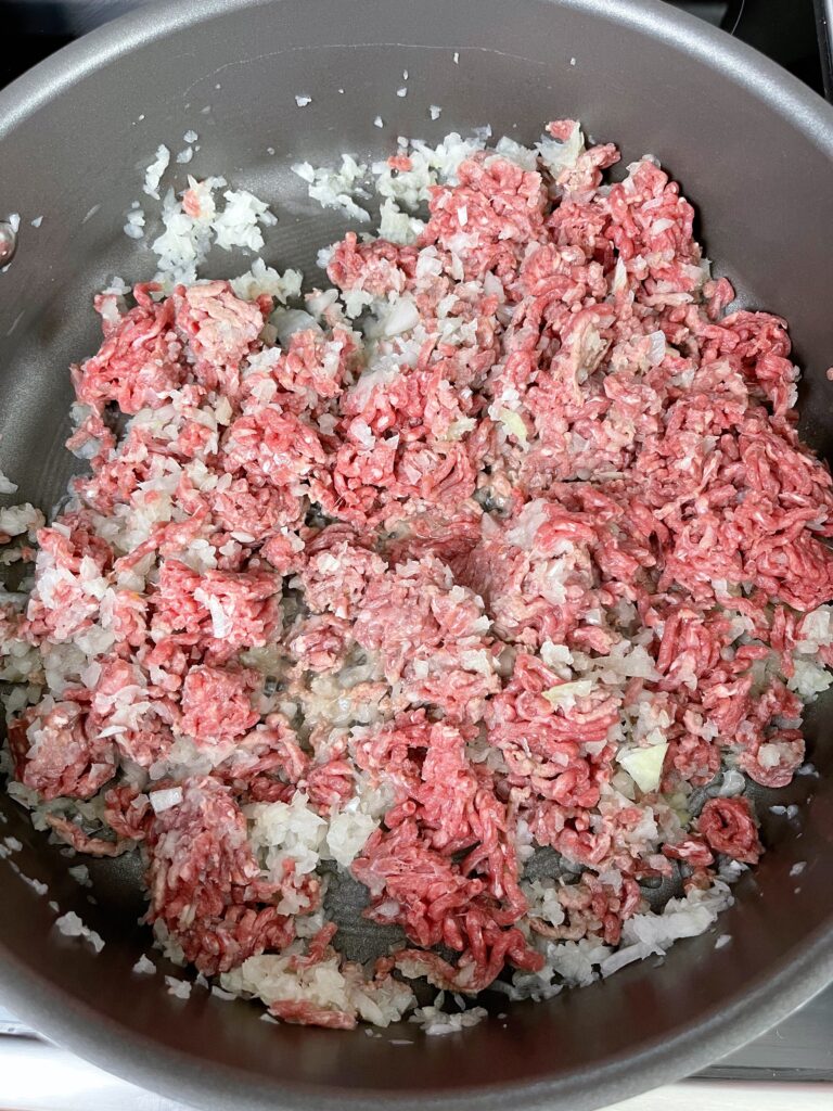 Ground beef and onion in a pan to make spaghetti sauce.