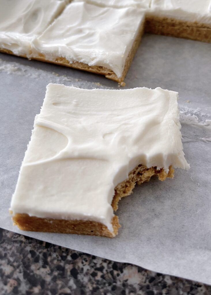 A pumpkin sugar cookie bar with a bite taken out.