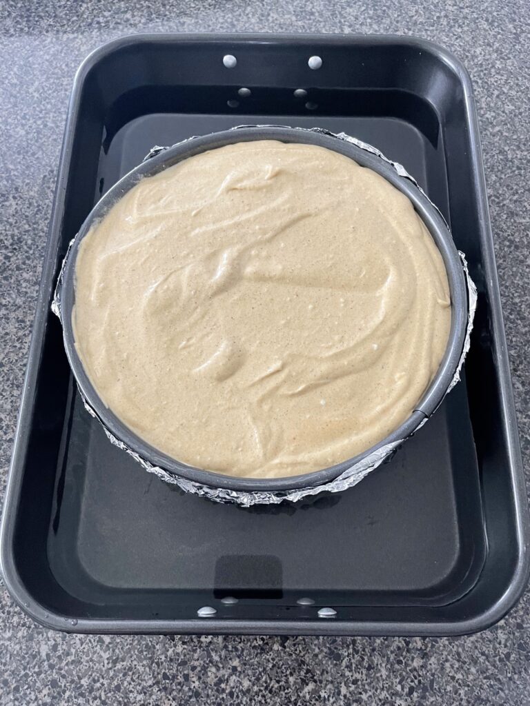 Pumpkin cheesecake batter in a springform pan inside a water bath.