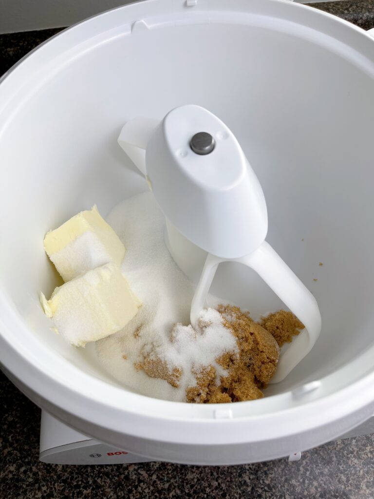 Butter, sugar, and brown sugar in the bowl of a stand mixer.