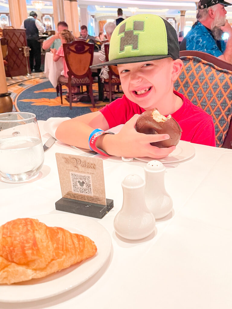 A child eating a donut for breakfast on a Disney Cruise.