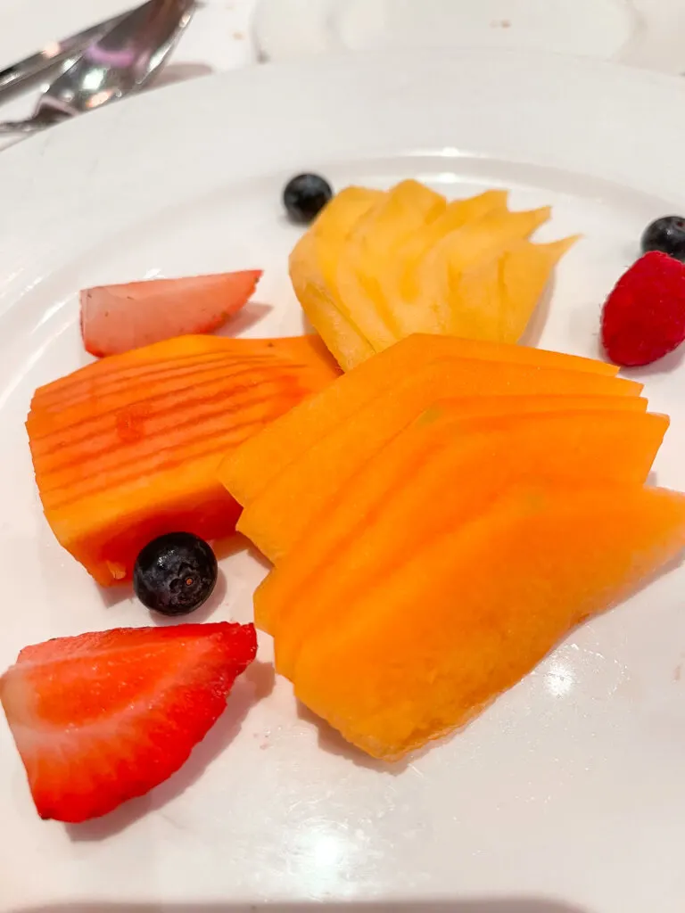 Fresh fruit on a white plate from Disney Cruise breakfast.