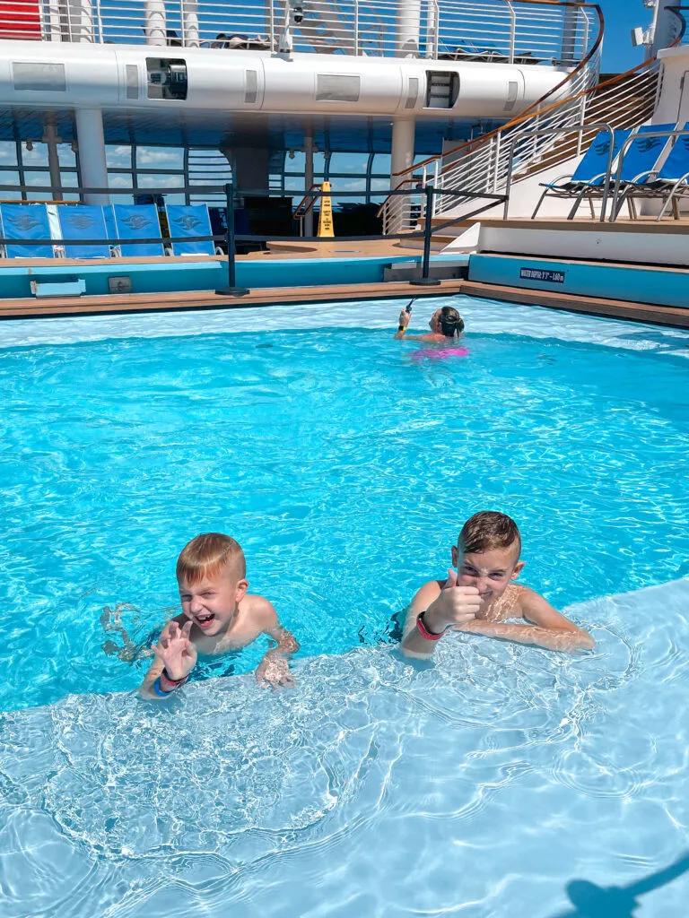 Two kids swimming in a pool on the Disney Dream.