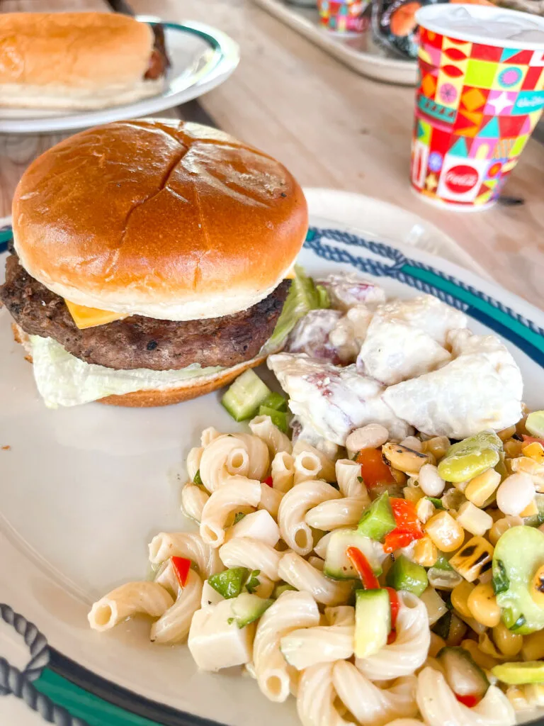 A plate of food with a cheeseburger and salads from Cookies BBQ on Castaway Cay.