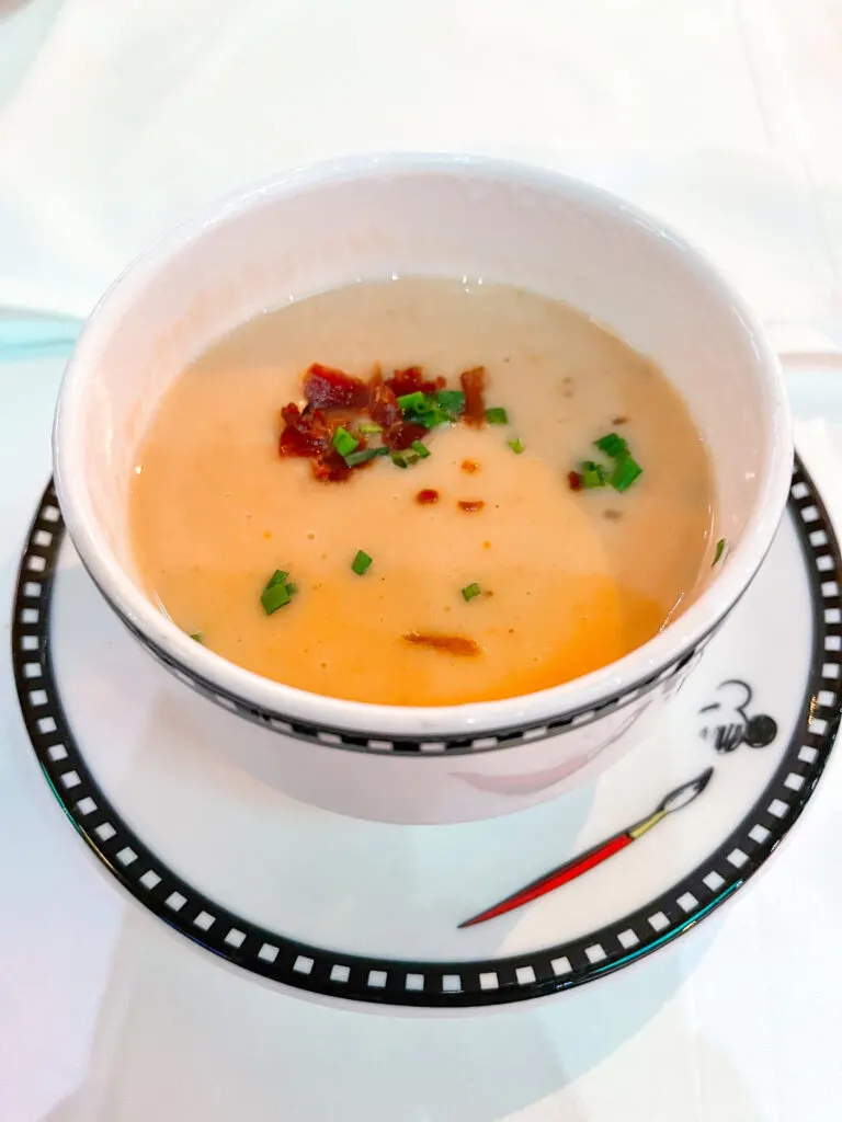 Baked Potato and Cheddar Cheese Soup with bacon and chives in a white bowl from Disney Cruise Line's Animator's Palate.