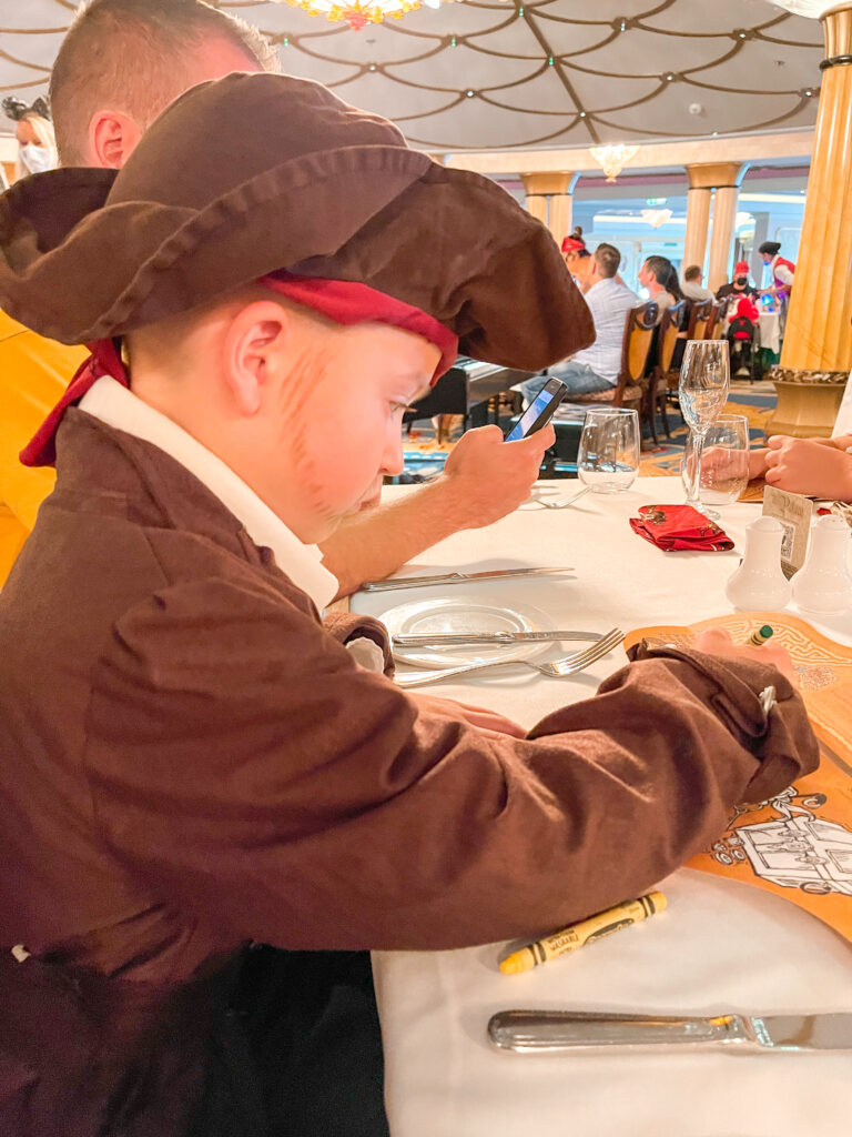 A boy dressed as a pirate coloring his kids meal menu on the Disney Dream.