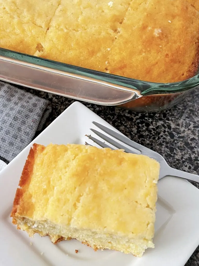 A piece of sweet moist cornbread on a plate with a fork.