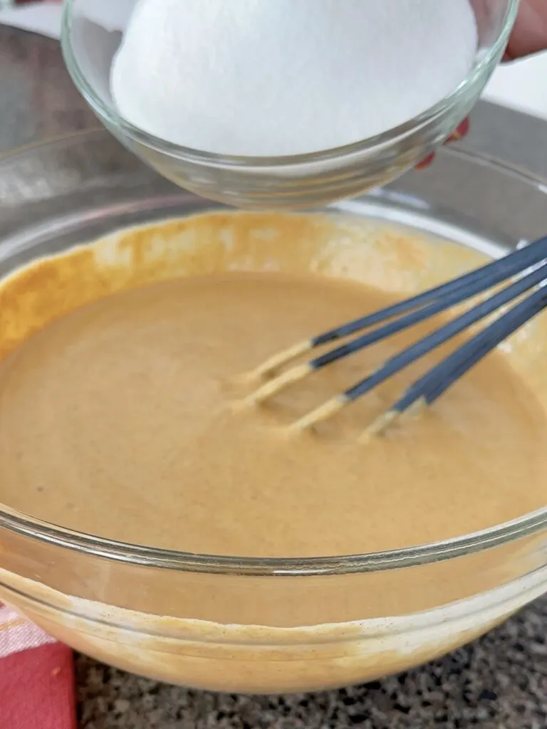 Pumpkin pie batter with a whisk in a bowl.
