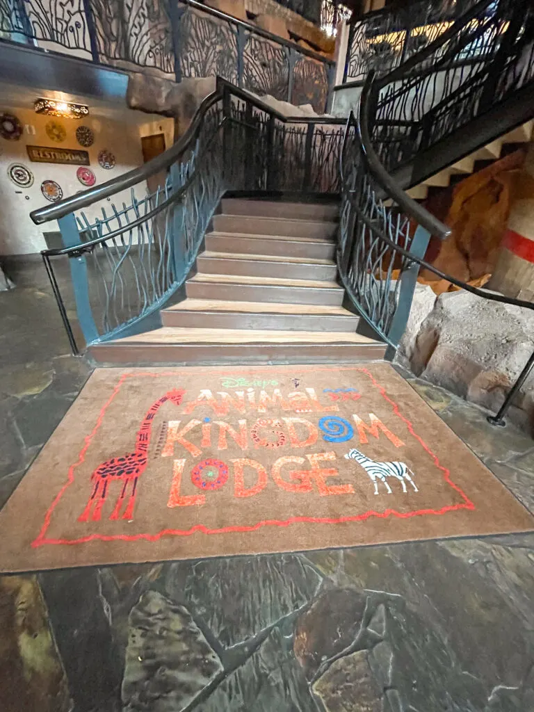 A rug at the bottom of a flight of stairs that says Disney's Animal Kingdom Lodge.
