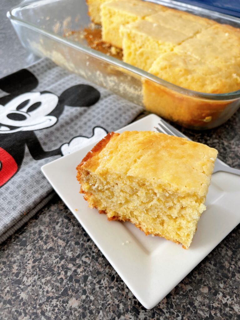 A slice of cornbread next to a Mickey Mouse kitchen Towel.