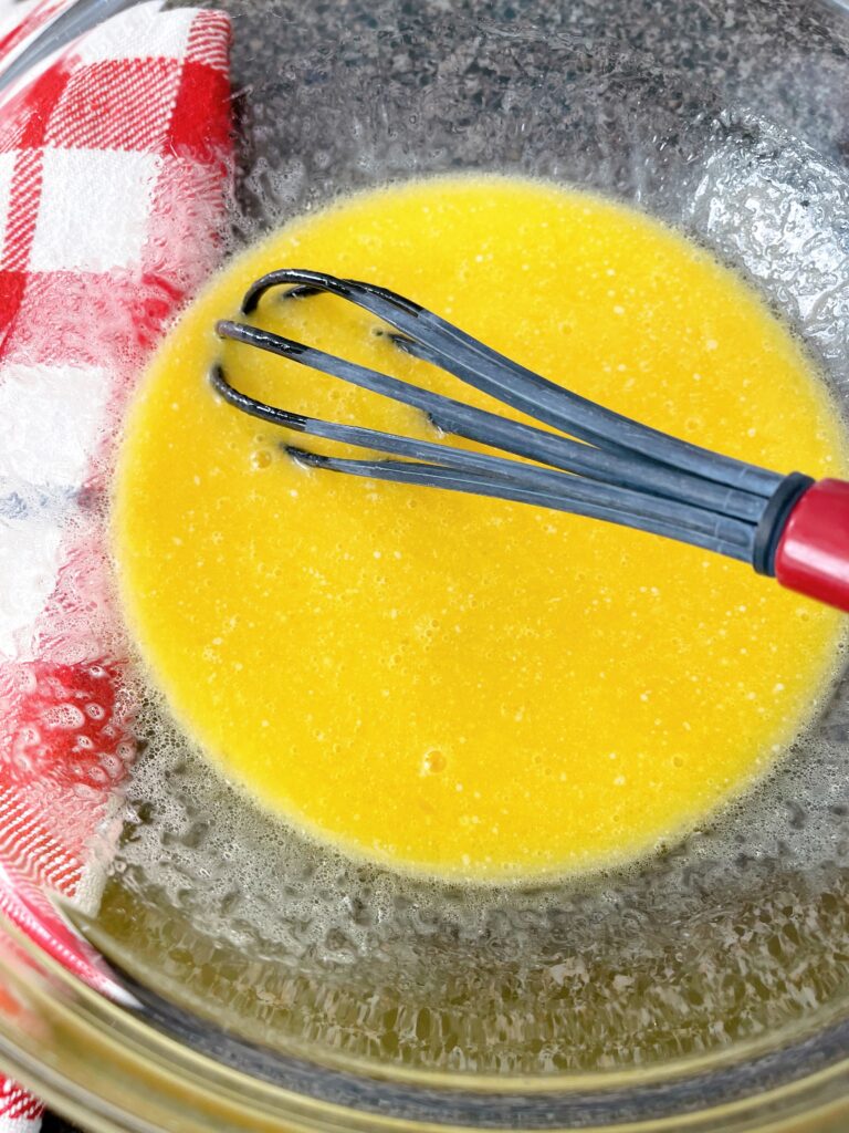 Eggs, butter, oil, sugar, and honey mixed together in a bowl to make cornbread.