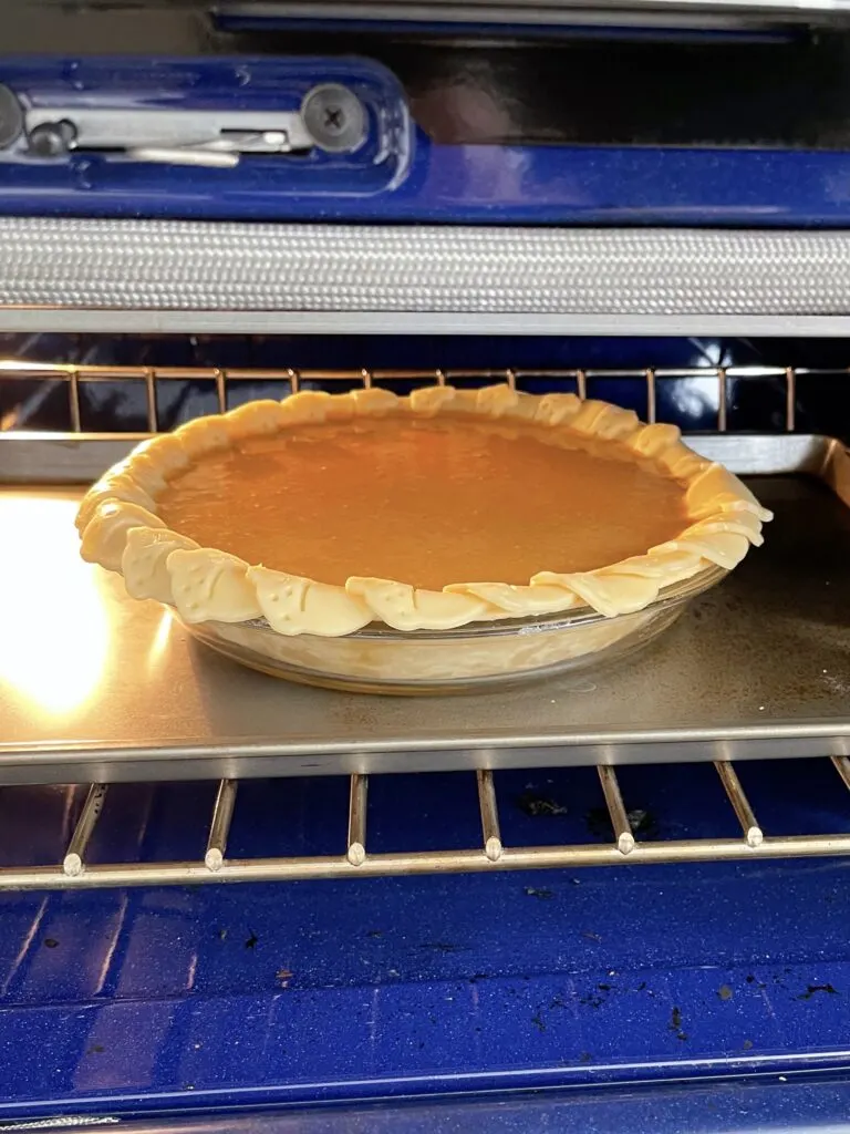 A copycat Costco pumpkin pie baking in an oven.