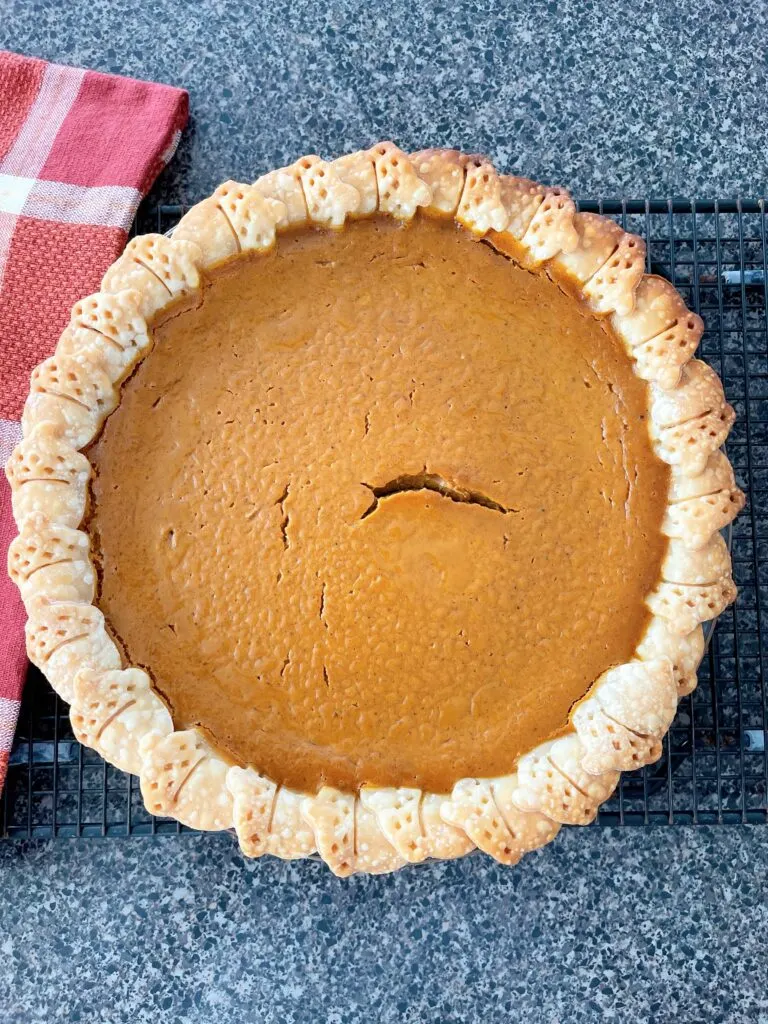 A pumpkin pie on a cooling rack.