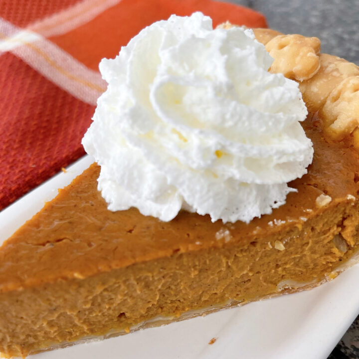 A slice of homemade Costco pumpkin pie with whipped cream.