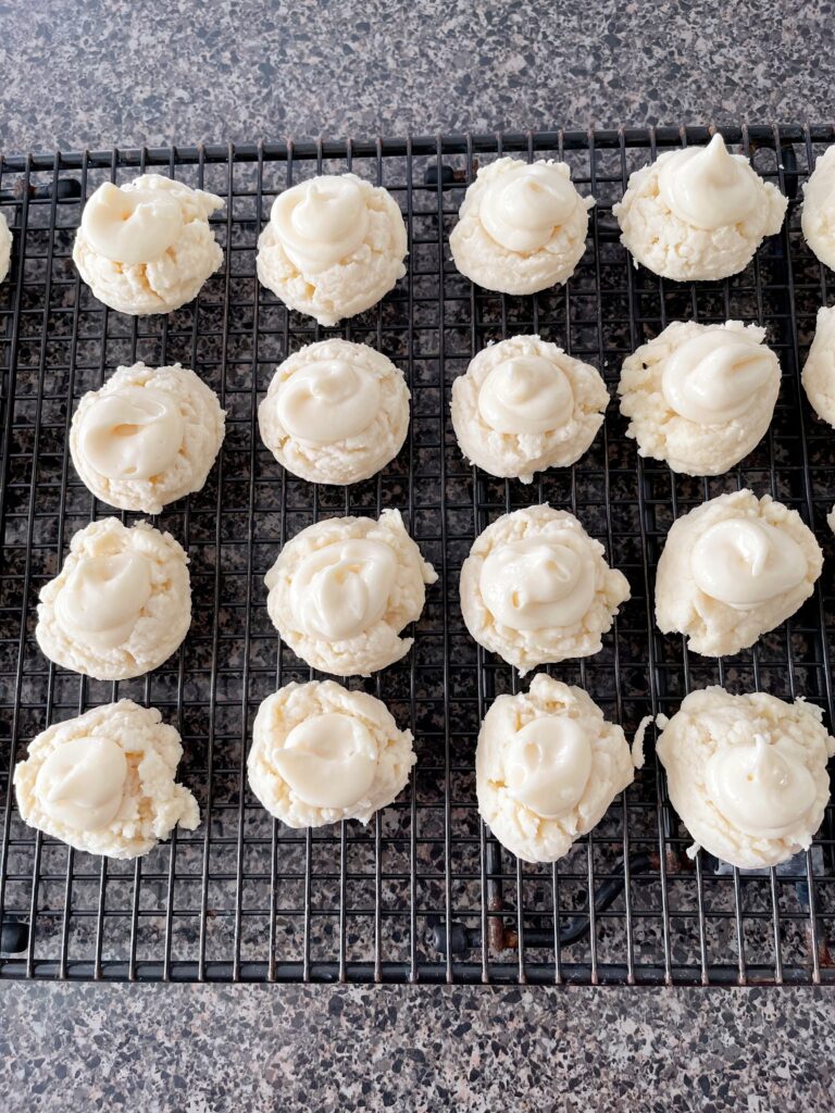 Christmas melt away cookies with cream cheese frosting on a cooling rack.