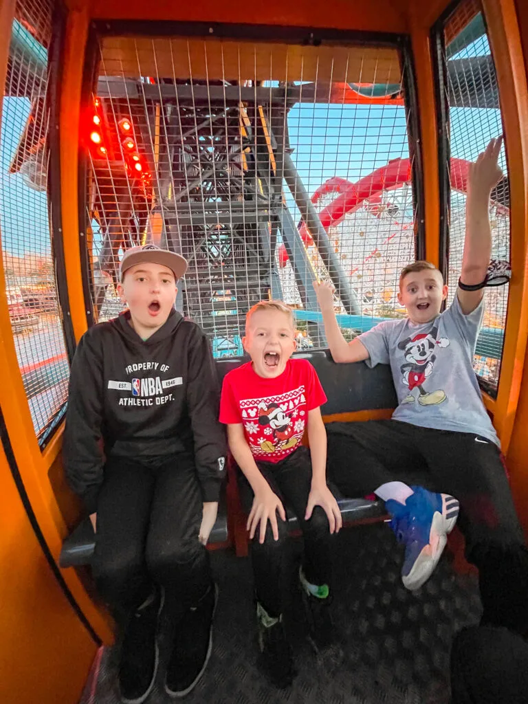 Three kids riding in a swinging gondola on Pixar Pal-A-Round at Disneyland.